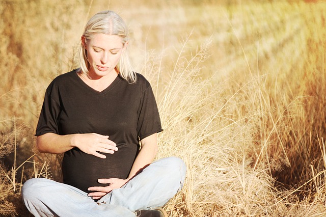 Kobieta w ciąży siedzi na łące