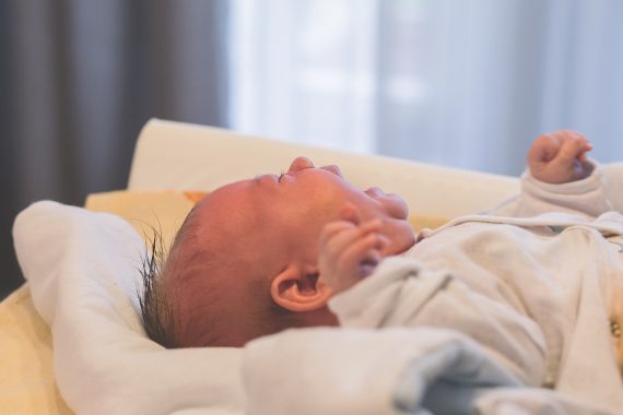 Niemowlę leżące na plecach i płaczące, co może wskazywać na objawy kolki jelitowej.
