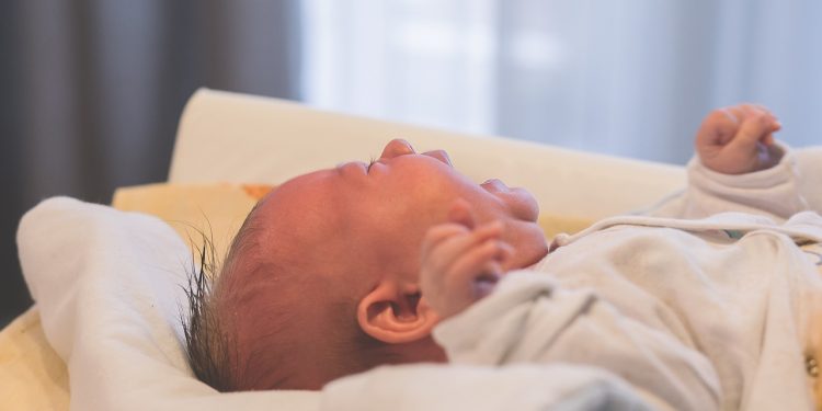 Niemowlę leżące na plecach i płaczące, co może wskazywać na objawy kolki jelitowej.