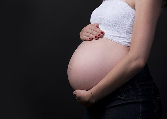 Kobieta ciężarna trzyma się za brzuch