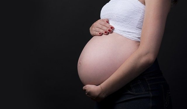Kobieta ciężarna trzyma się za brzuch