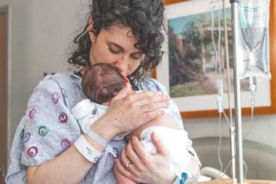 Mama po cesarskim cięciu trzyma na rękach noworodka