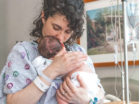Mama po cesarskim cięciu trzyma na rękach noworodka