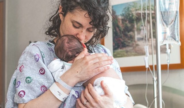 Mama po cesarskim cięciu trzyma na rękach noworodka